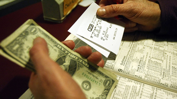 NEW YORK - MARCH 1:  A man holds his betting slips and money at an Off-Track Betting (OTB) parlor in Midtown Manhattan March 1, 2008 in New York City. The board that oversees New York City's OTB operations voted last week to close all 71 parlors by mid-June since the city does not want to subsidize the gambling outposts. State officials are contesting the ruling.  (Photo by Mario Tama/Getty Images)